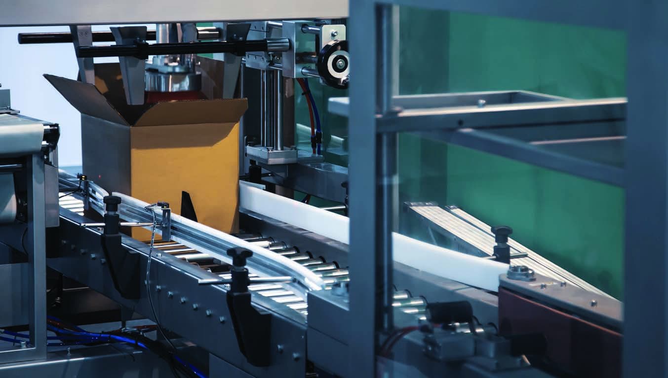 Automated packaging equipment line moving a carton on a conveyor